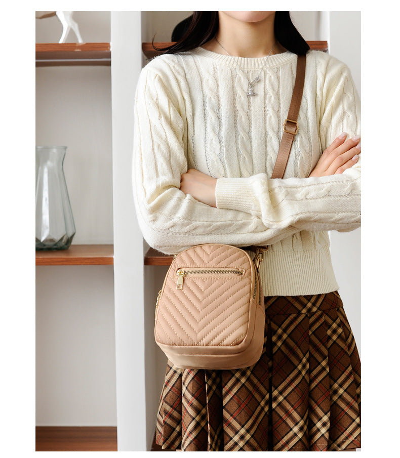 A stylish nylon quilted bag featuring multiple zipper pockets, adjustable strap, and gold-tone hardware.