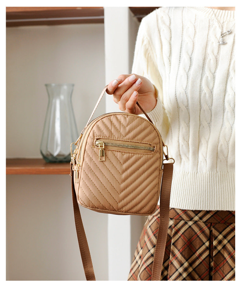 A stylish nylon quilted bag featuring multiple zipper pockets, adjustable strap, and gold-tone hardware.