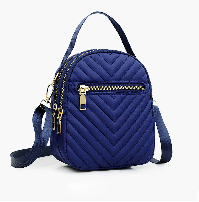 A stylish nylon quilted bag featuring multiple zipper pockets, adjustable strap, and gold-tone hardware.