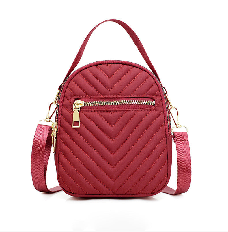 A stylish nylon quilted bag featuring multiple zipper pockets, adjustable strap, and gold-tone hardware.