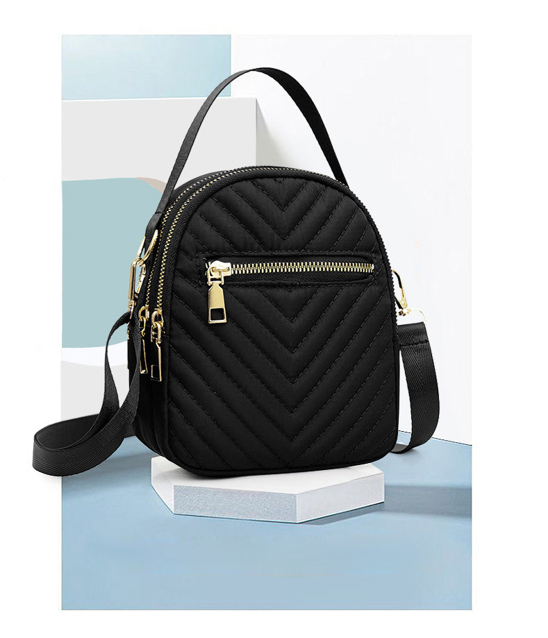 A stylish nylon quilted bag featuring multiple zipper pockets, adjustable strap, and gold-tone hardware.