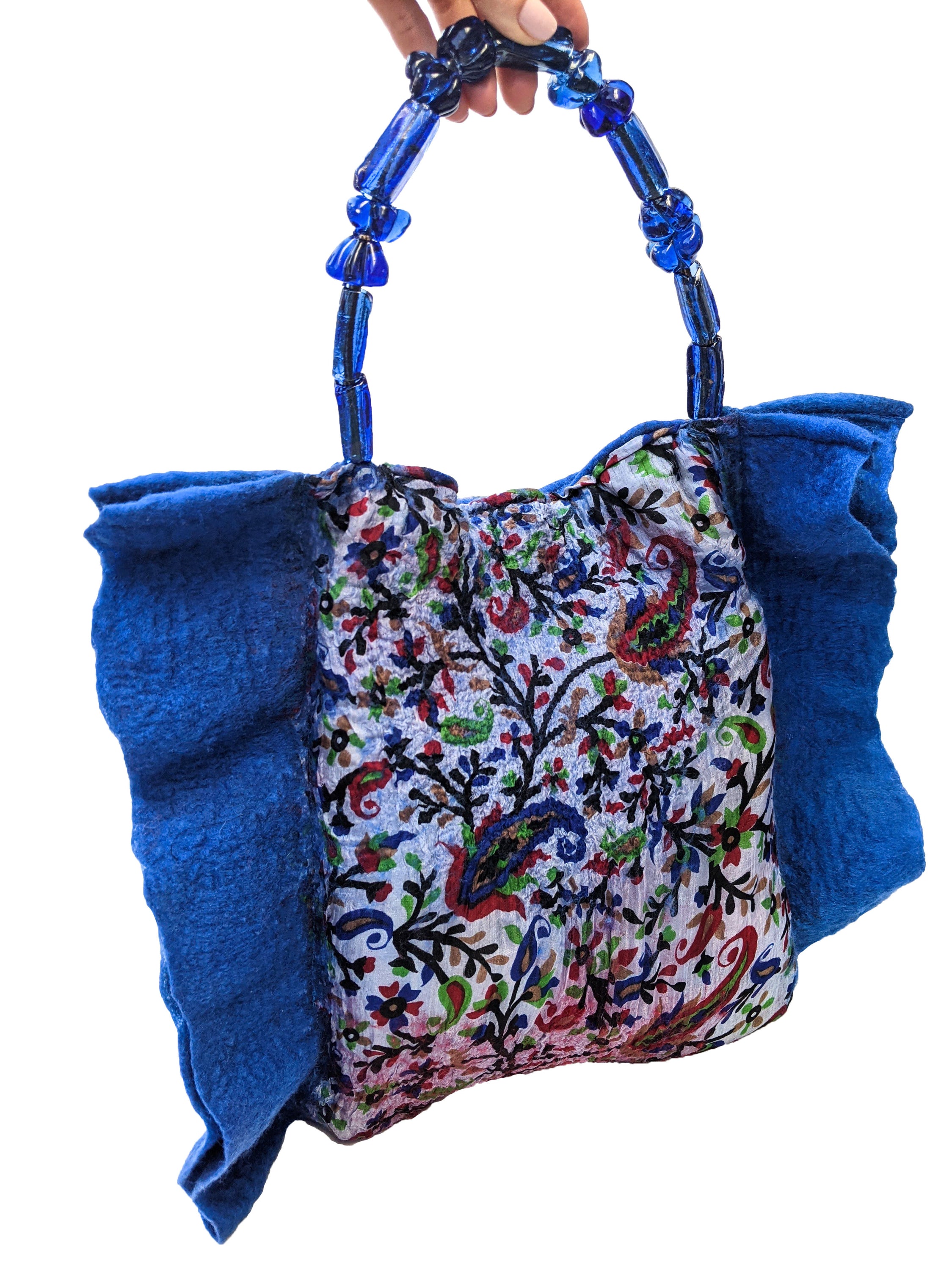 Handmade cobalt blue felt bag with glass bead handle and linen lining, featuring a snap fastener closure.