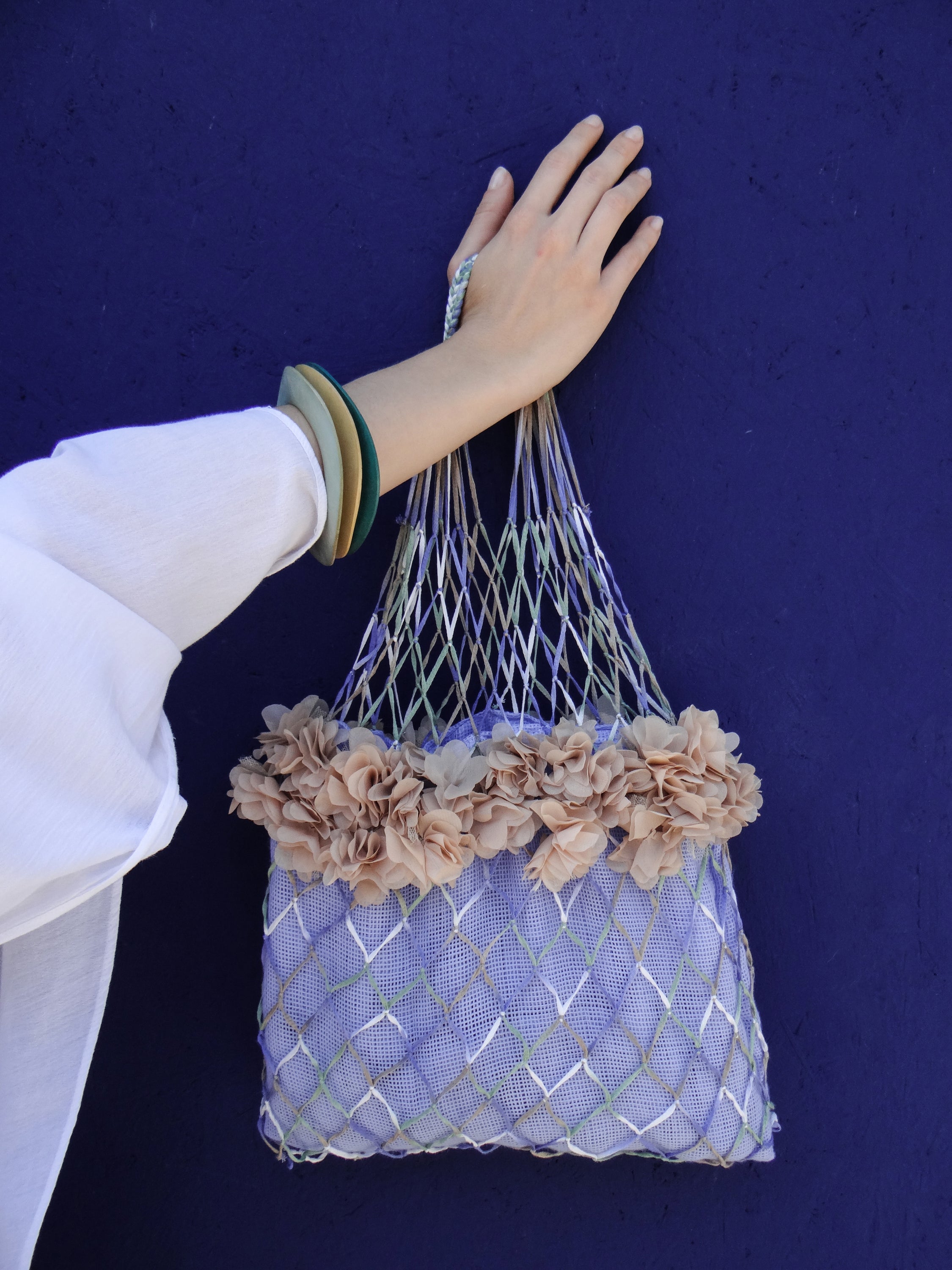 Handmade blue-green fishnet bag with floral decorations and blue cotton lining, perfect for beach outings.