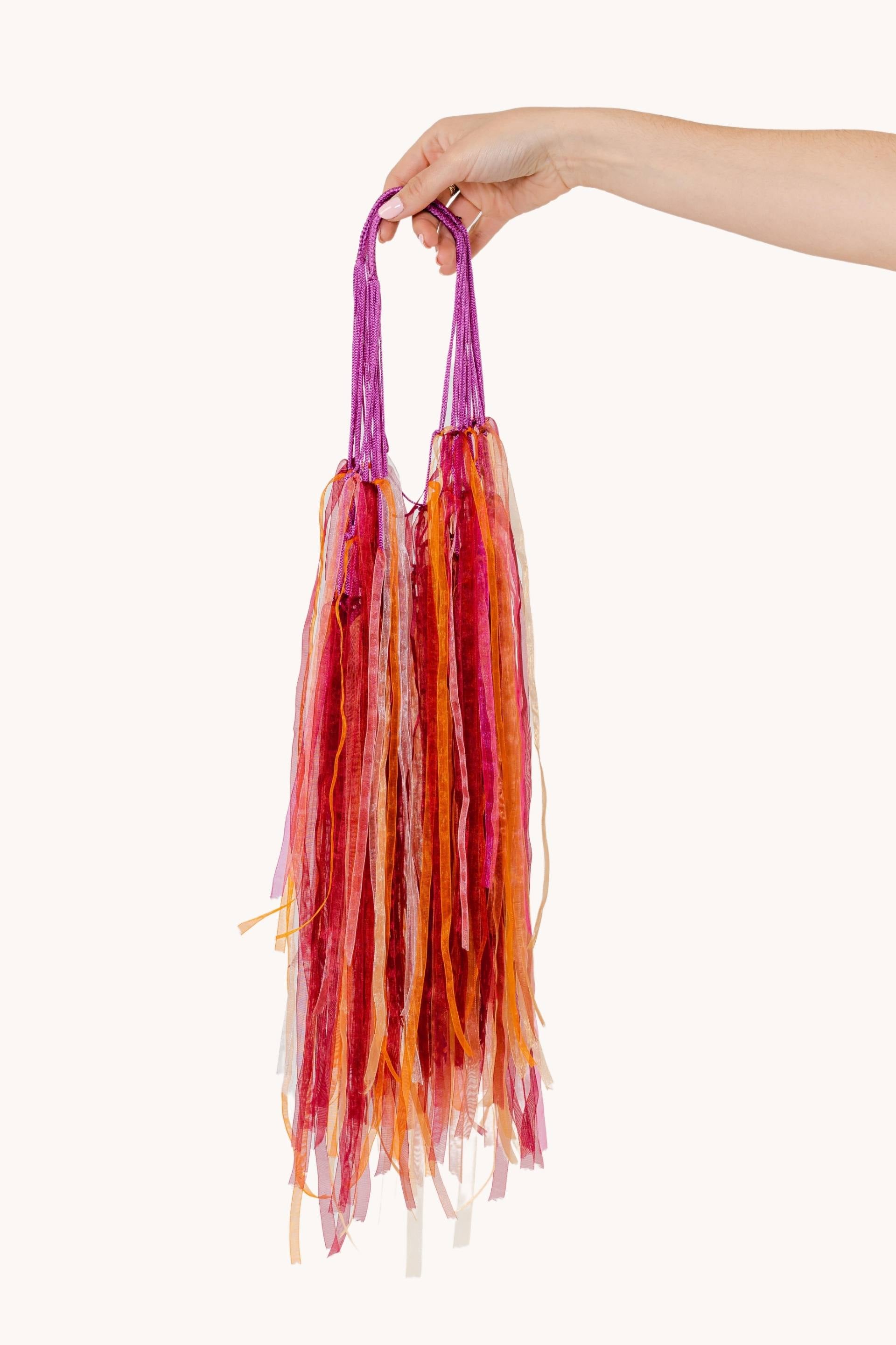 A vibrant Pink Jelly fishnet bag adorned with pink, orange, and purple ribbons, perfect for summer outings.