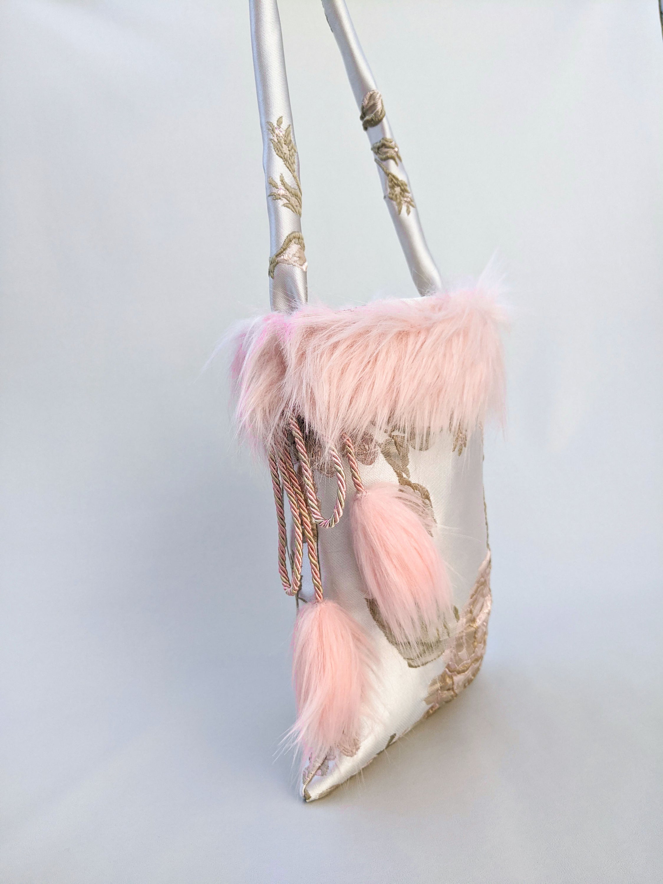 Poppyseed Jasper pouch bag featuring jacquard fabric, pink faux fur details, and a gold-rose cord closure, measuring 17 cm x 26 cm.