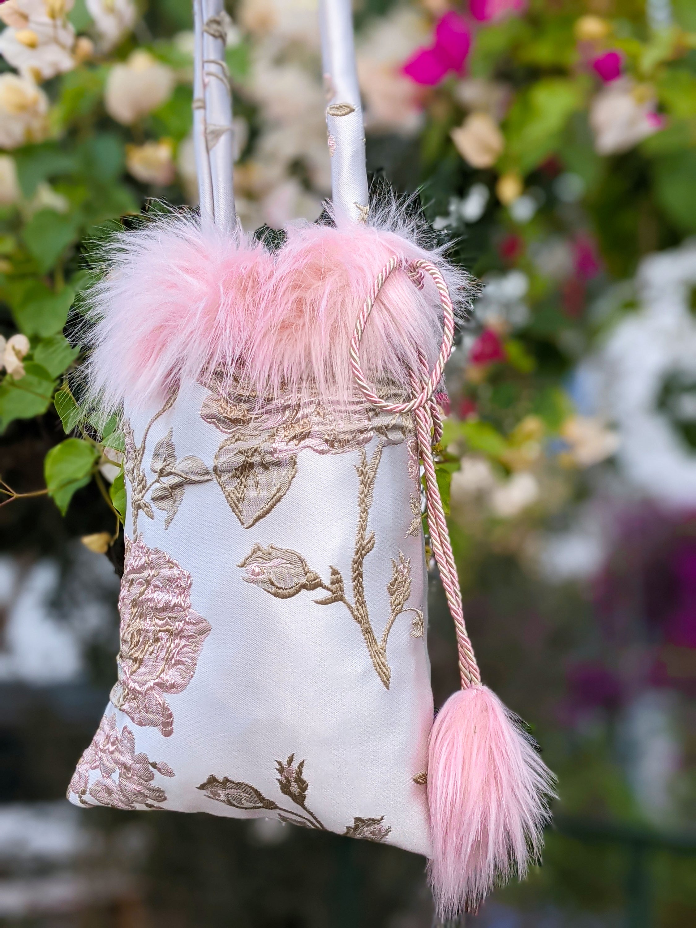 Poppyseed Jasper pouch bag featuring jacquard fabric, pink faux fur details, and a gold-rose cord closure, measuring 17 cm x 26 cm.