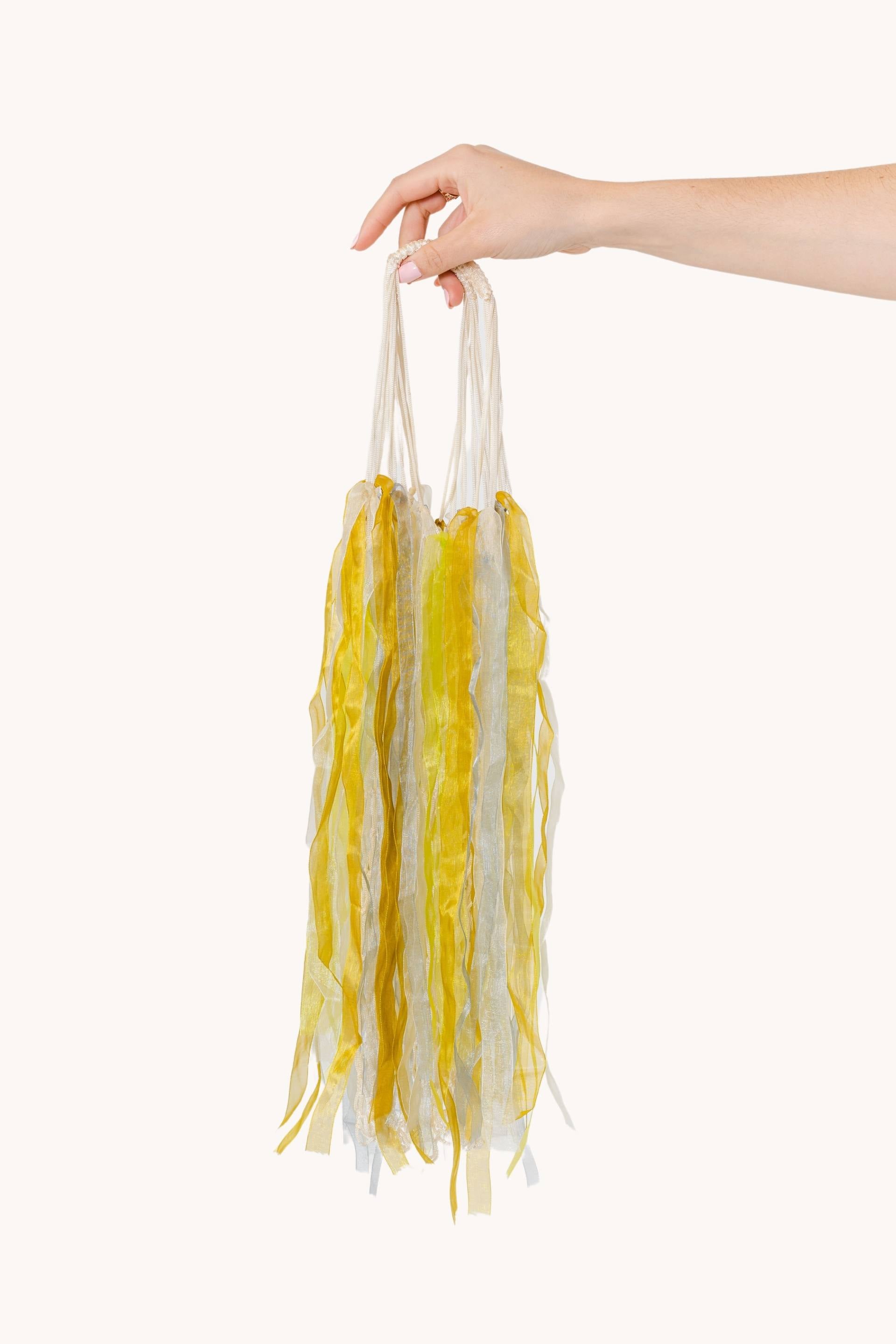 A beautiful Rainbow Jelly decoration featuring a white fishnet bag adorned with pastel yellow ribbons, refracting light to create a rainbow effect.