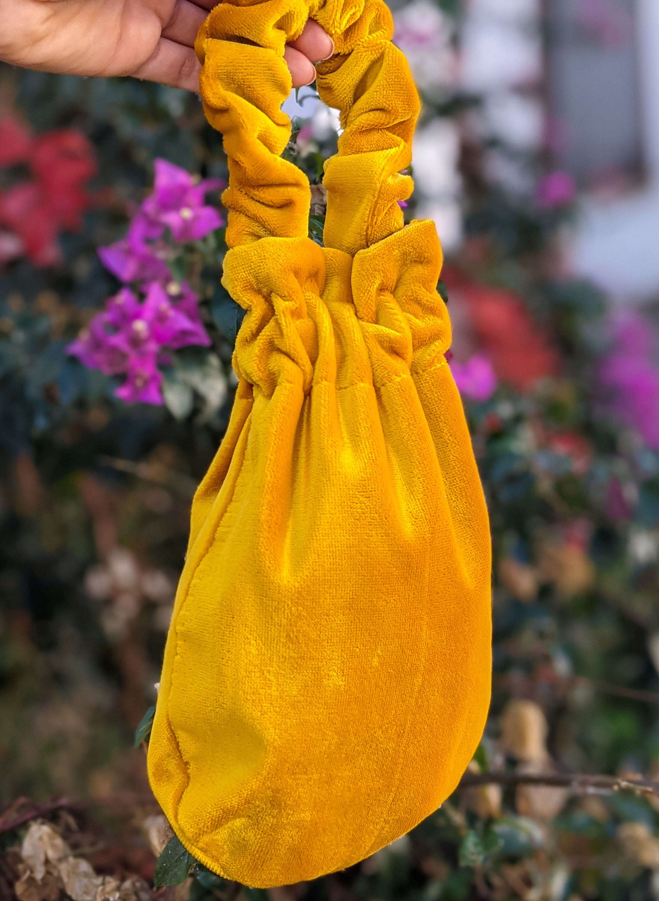 A stylish deep yellow velvet wristlet bag with a sleek design, perfect for various occasions.