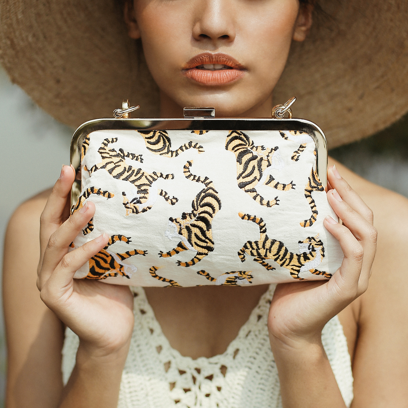 Ivory white Sumatran Tiger Clutch featuring handwoven raw cotton fabric, intricate embroidery, and a gold metal chain strap, symbolizing wildlife conservation.