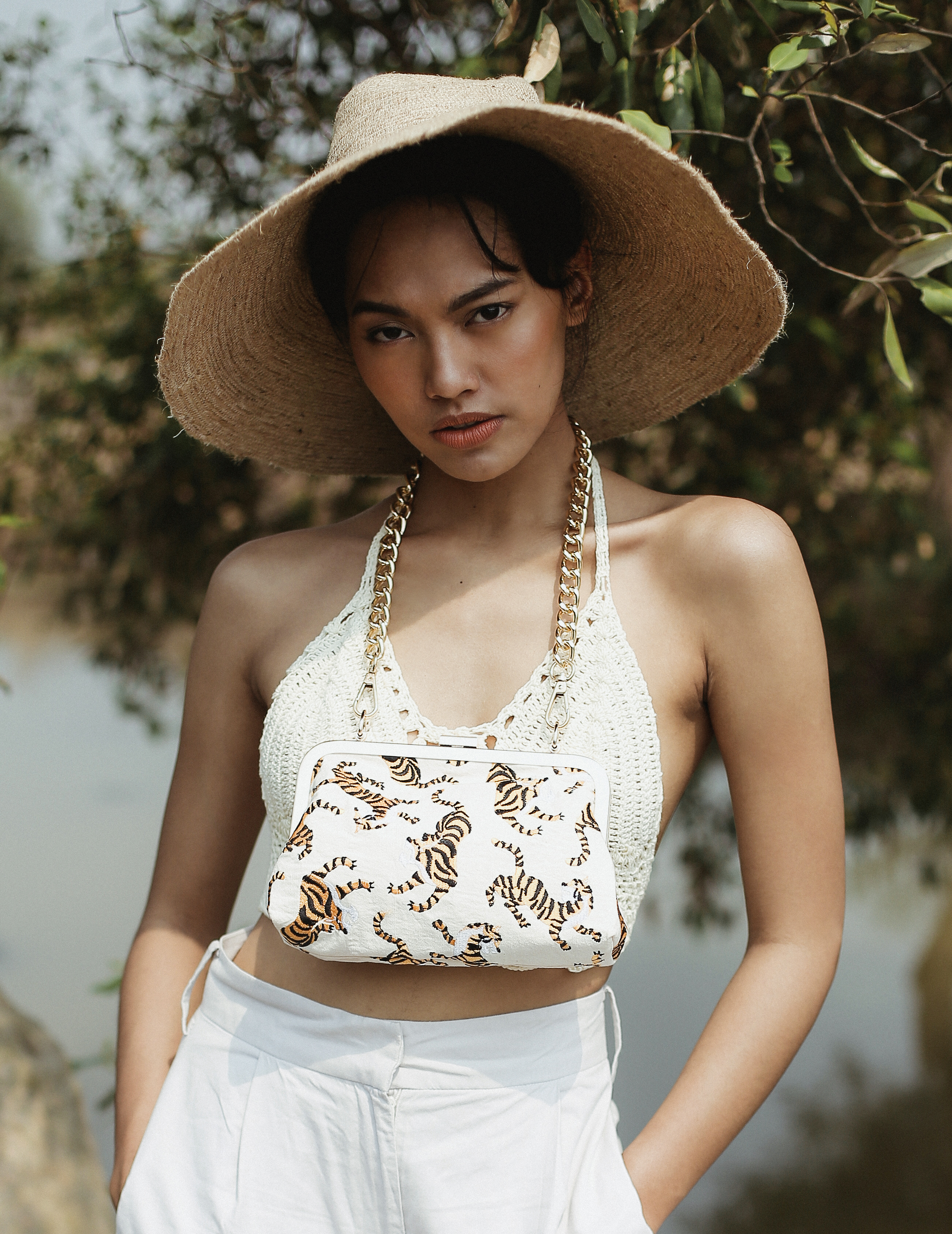 Ivory white Sumatran Tiger Clutch featuring handwoven raw cotton fabric, intricate embroidery, and a gold metal chain strap, symbolizing wildlife conservation.