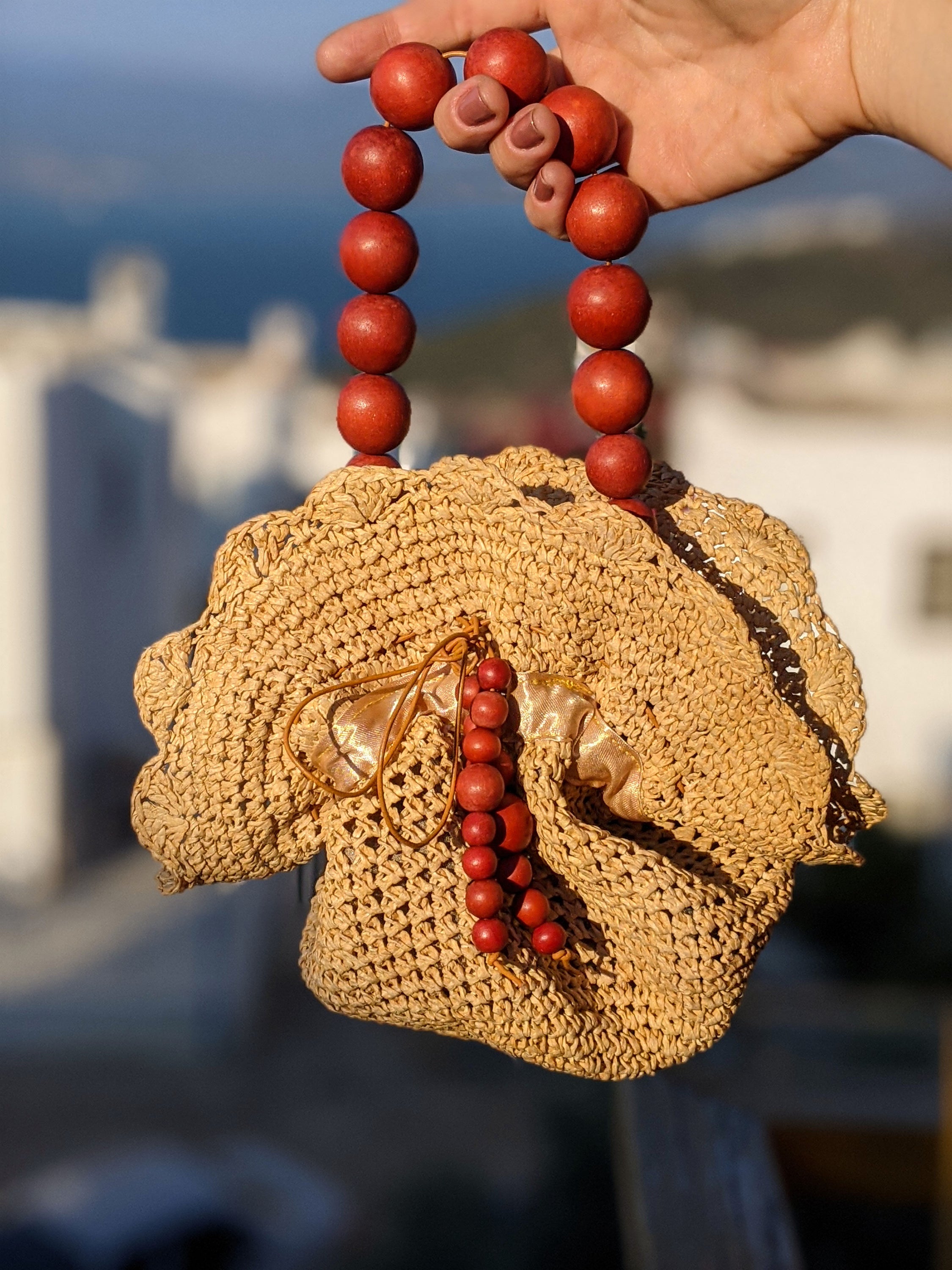 Upcycled straw pouch bag featuring a drawstring closure, wooden bead handle, and snap fastener, showcasing eco-friendly fashion.