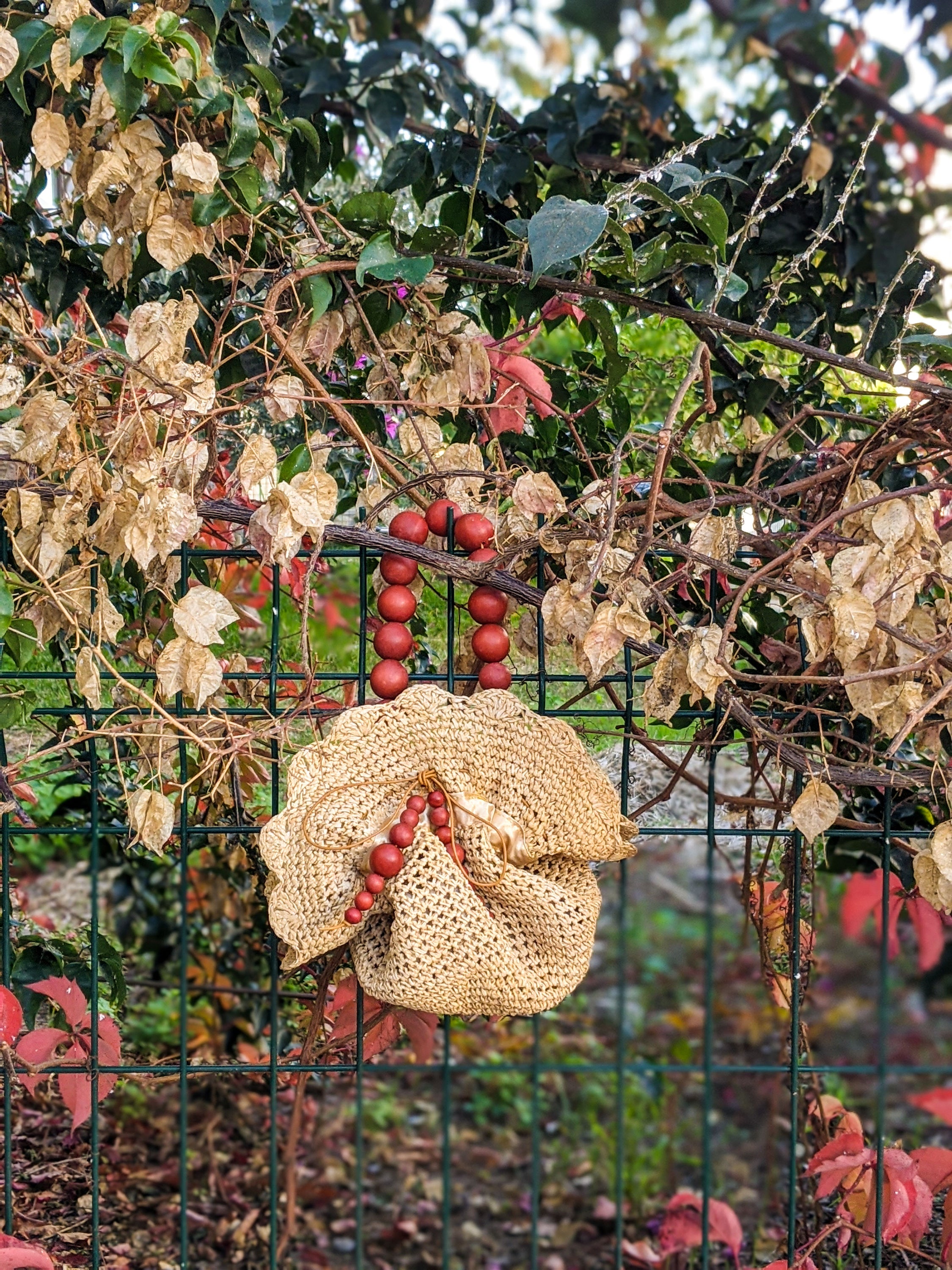 Upcycled straw pouch bag featuring a drawstring closure, wooden bead handle, and snap fastener, showcasing eco-friendly fashion.