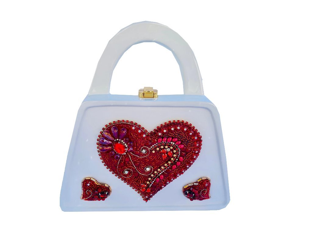 Valentina Handbag featuring a glossy white finish, wood top handle, and hand-beaded red hearts, showcasing its unique design and craftsmanship.