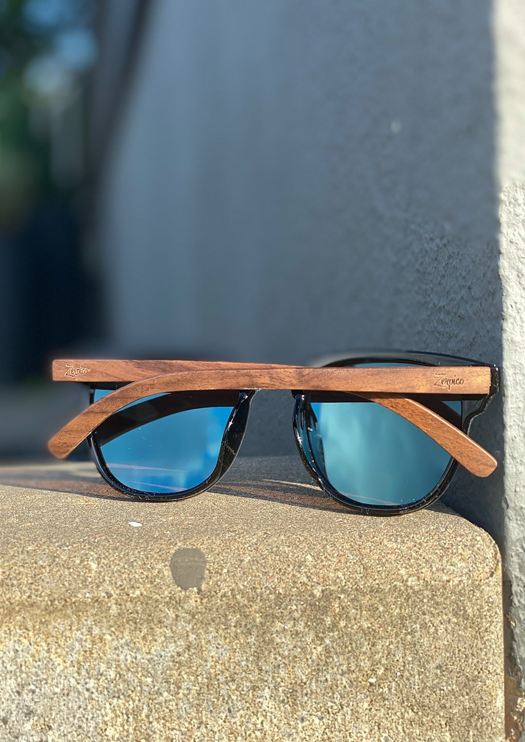 Eyewood Tomorrow - Delphinus wooden sunglasses featuring walnut temples and blue mirror polarized lenses, elegantly displayed in a natural setting.