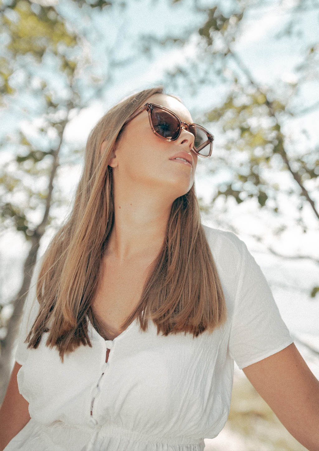 A pair of Jasmine sunglasses from the Babylon Series featuring a classic wayfarer shape and vibrant colors, set against a rustic wooden background.