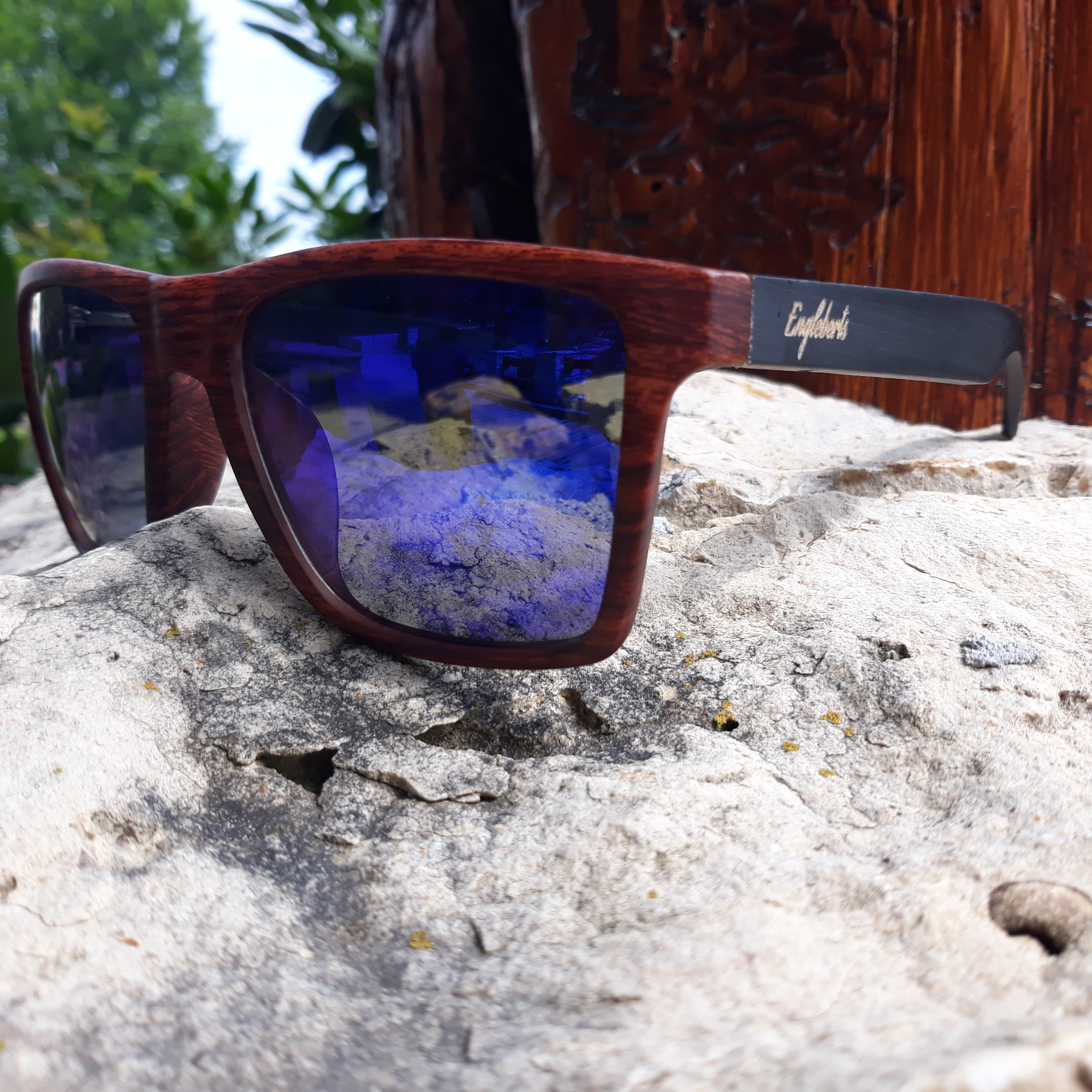 Stylish oak colored bamboo sunglasses with blue polarized lenses, displayed with a bamboo case and accessories.