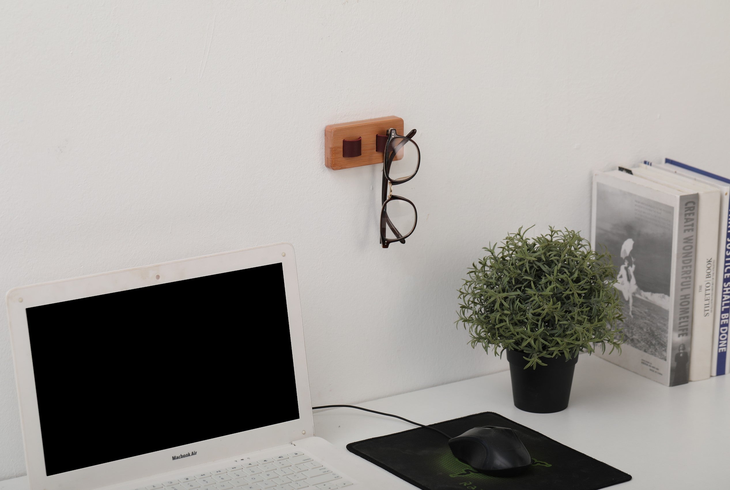 Wood eye glasses holder mounted on a wall, featuring leather straps for sunglasses and a bamboo base, showcasing an organized eyewear collection.