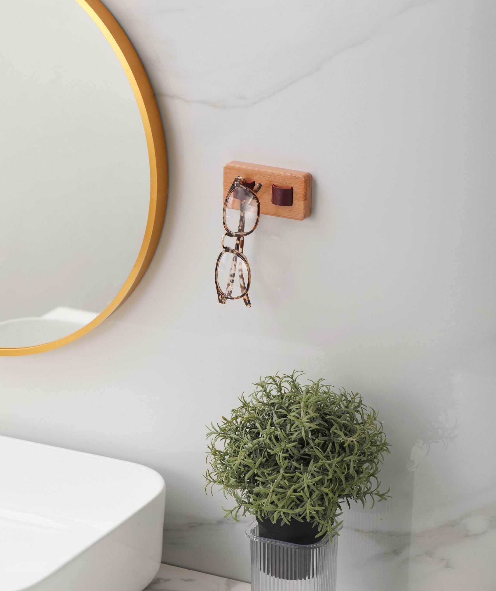 Wood eye glasses holder mounted on a wall, featuring leather straps for sunglasses and a bamboo base, showcasing an organized eyewear collection.