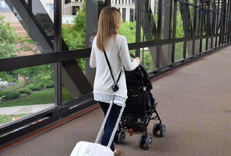 RetraStrap hands-free luggage strap attached to a wheeled carry-on, showcasing its ergonomic design and anti-theft features.