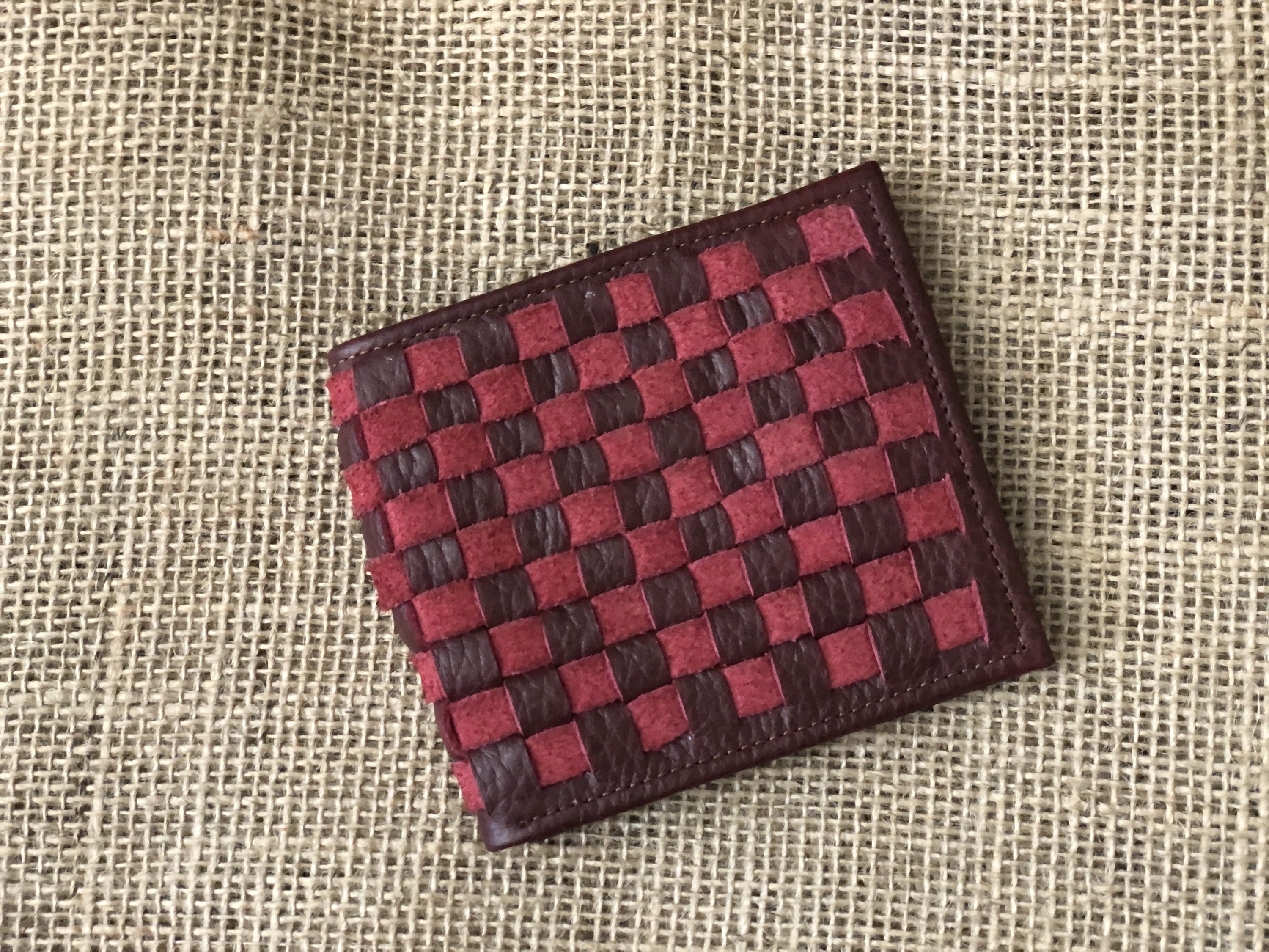 A stylish Leather Woven Bifold Wallet showcasing handwoven suede and smooth leather, featuring a magnetic bronze clasp and colorful cotton lining.