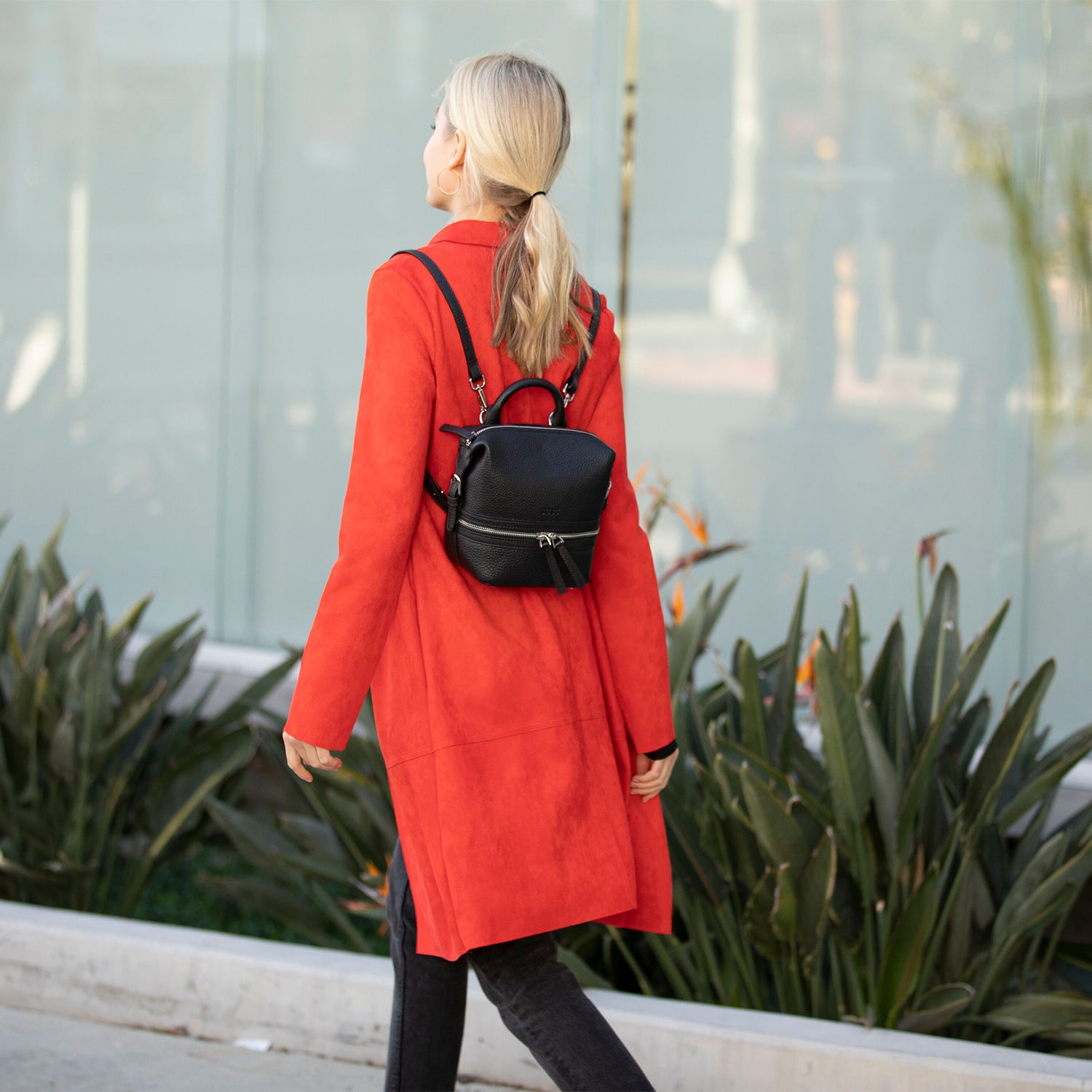 Ashley Small Black Leather Backpack featuring a sleek black exterior, red interior, and silver hardware, perfect for versatile styling.