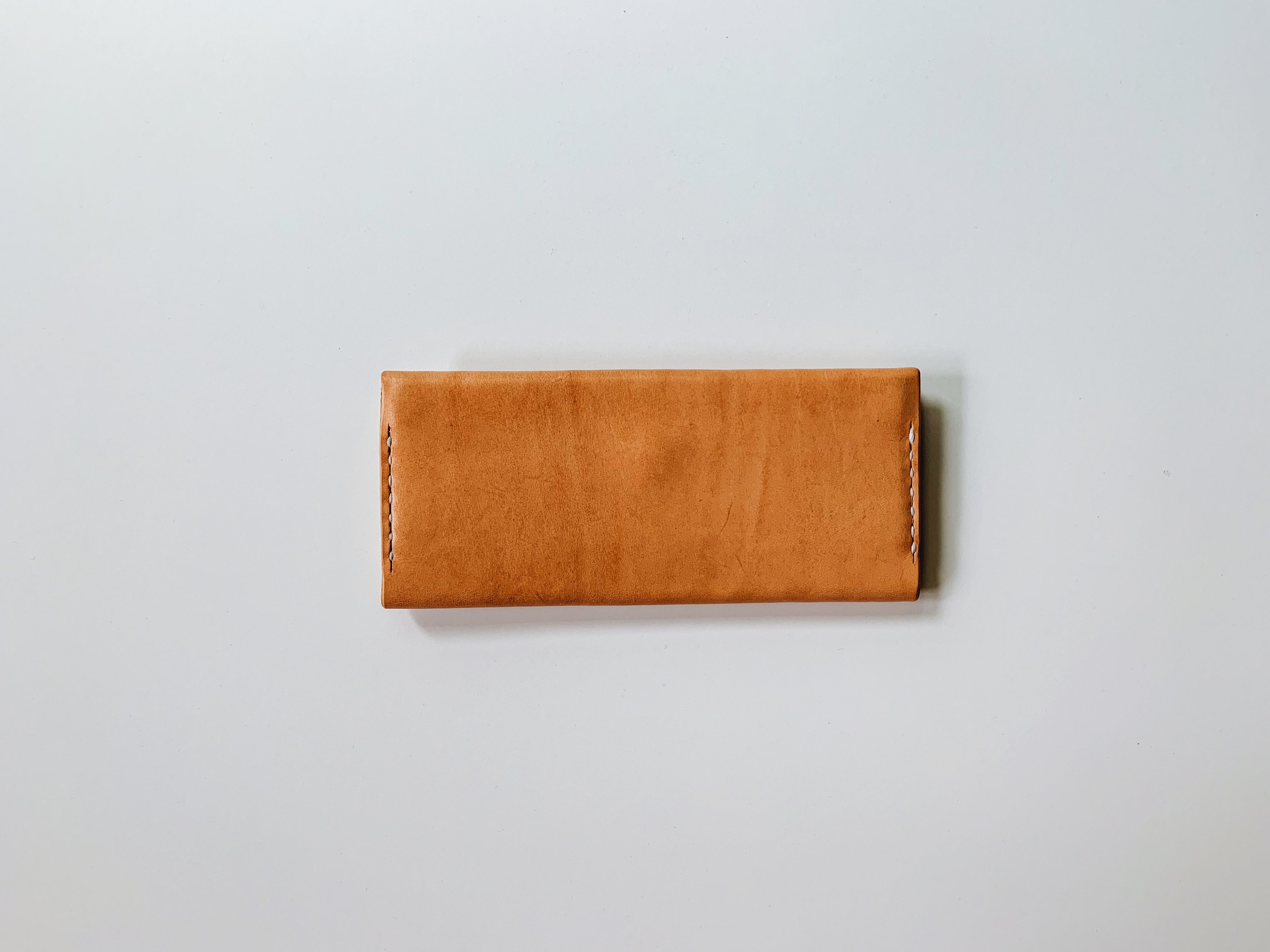 A sleek Women's Bifold Wallet made from vegetable-tanned leather, featuring card slots, a coin pouch, and a cash compartment.