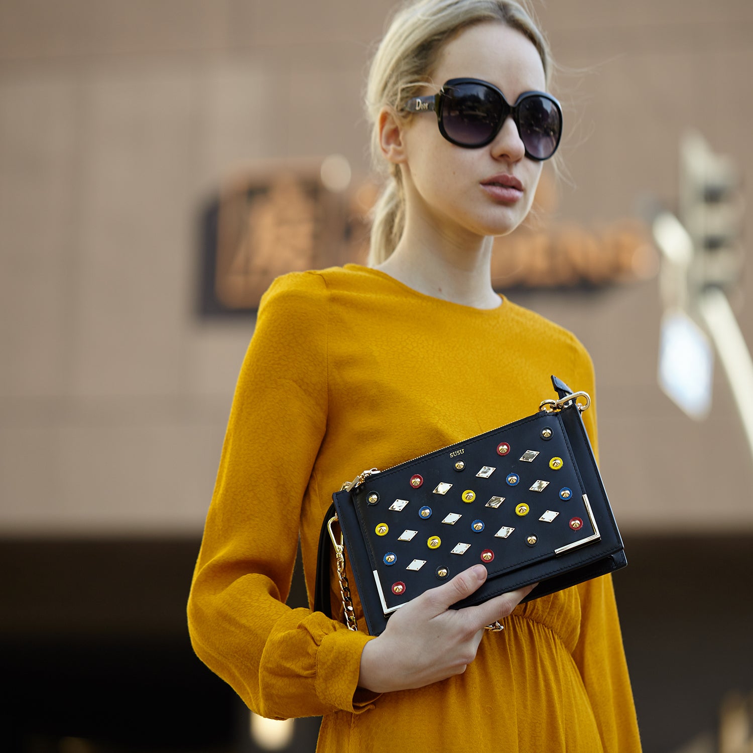 Black Studded Crossbody Clutch with gold chain and leather straps, featuring a chic square silhouette and zipped pockets.