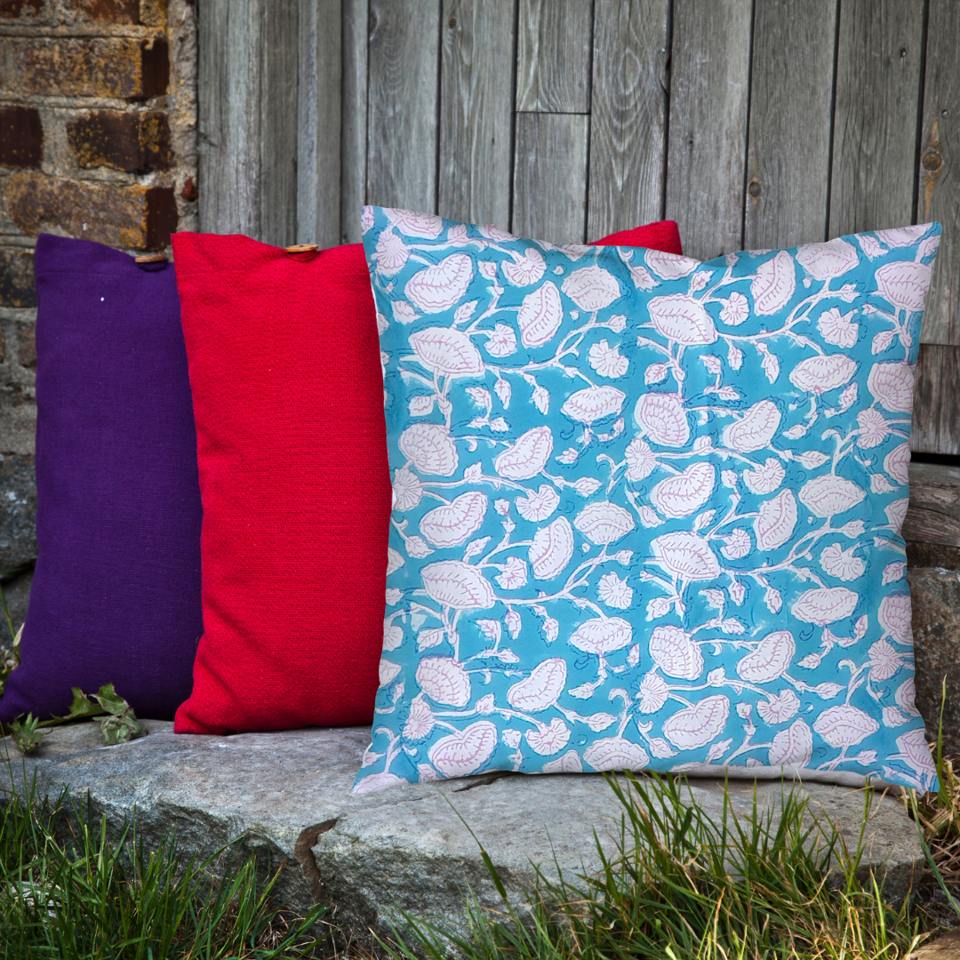 Handmade block-printed cushion cover featuring floral patterns in teal with pink outline, showcasing artisan craftsmanship.