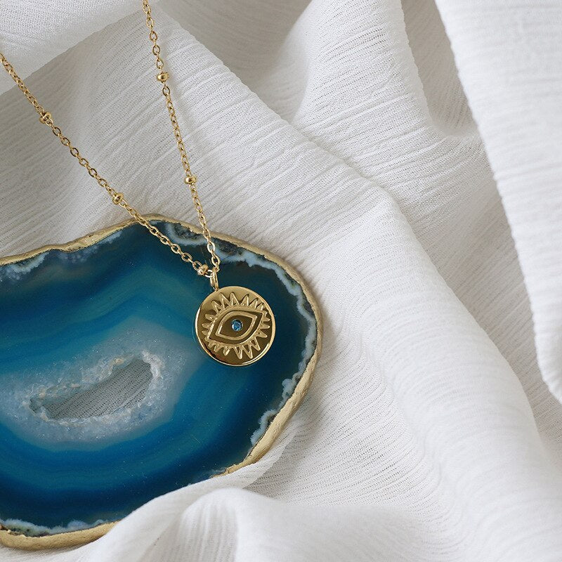 A stunning Blue Evil Eye Coins Necklace featuring a round pendant, 14k gold plating, and a link chain, perfect for women seeking style and protection.