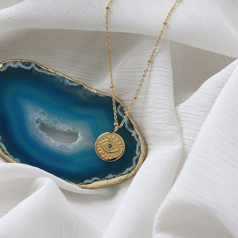 A stunning Blue Evil Eye Coins Necklace featuring a round pendant, 14k gold plating, and a link chain, perfect for women seeking style and protection.