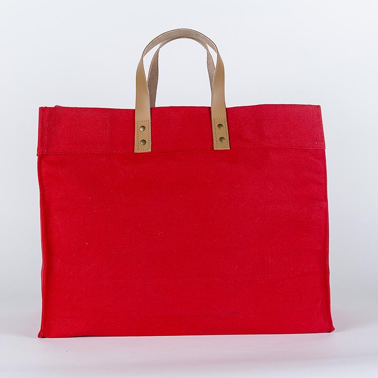 A stylish Box Tote Bag made of heavyweight canvas with thick leather handles and metal studs, perfect for outdoor gatherings.