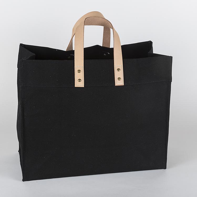 A stylish Box Tote Bag made of heavyweight canvas with thick leather handles and metal studs, perfect for outdoor gatherings.