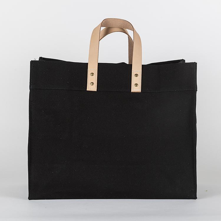 A stylish Box Tote Bag made of heavyweight canvas with thick leather handles and metal studs, perfect for outdoor gatherings.