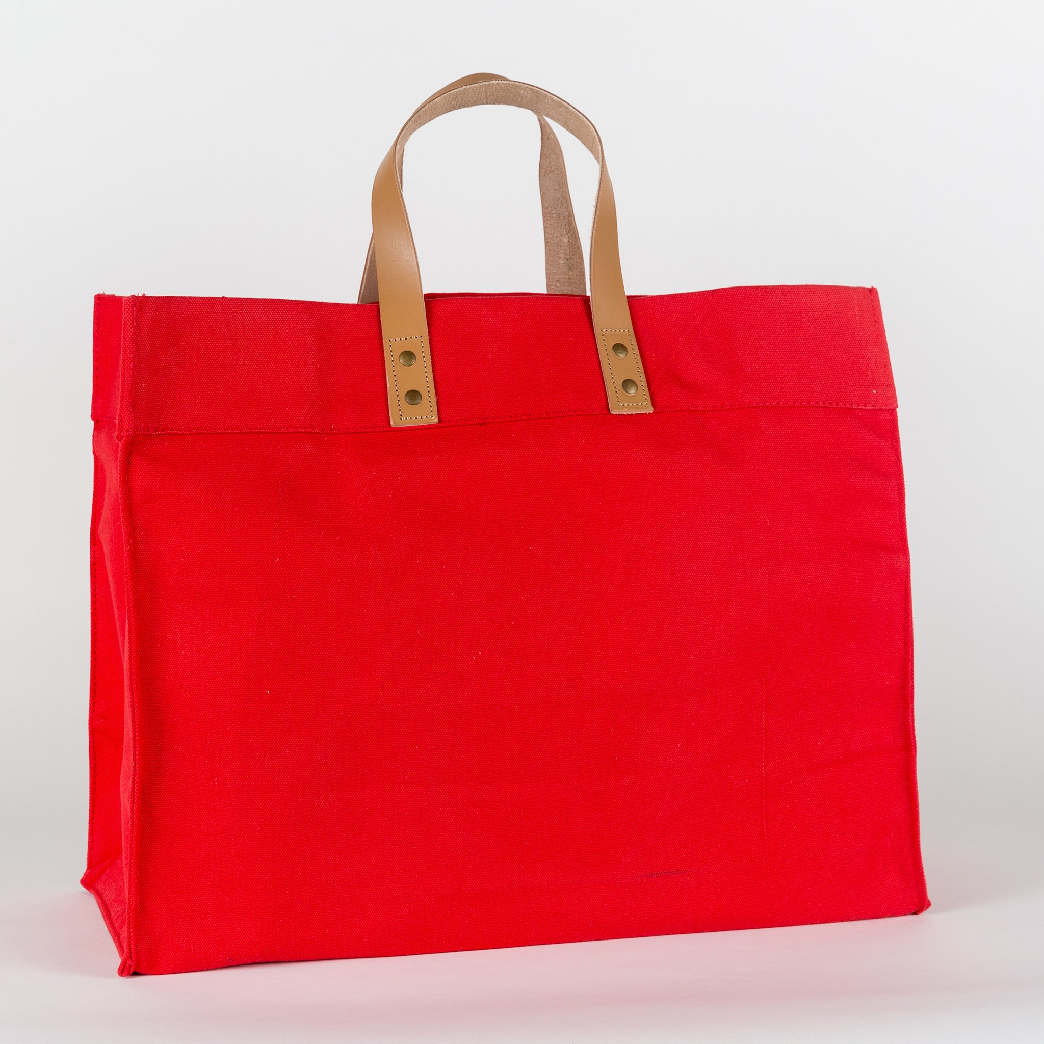 A stylish Box Tote Bag made of heavyweight canvas with thick leather handles and metal studs, perfect for outdoor gatherings.