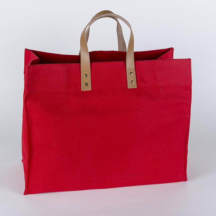 A stylish Box Tote Bag made of heavyweight canvas with thick leather handles and metal studs, perfect for outdoor gatherings.