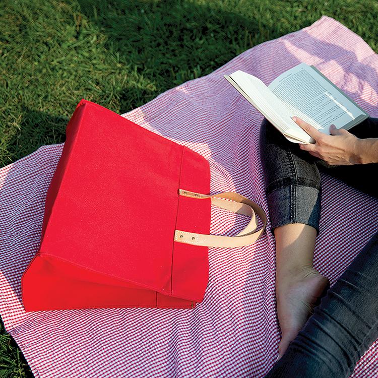 A stylish Box Tote Bag made of heavyweight canvas with thick leather handles and metal studs, perfect for outdoor gatherings.