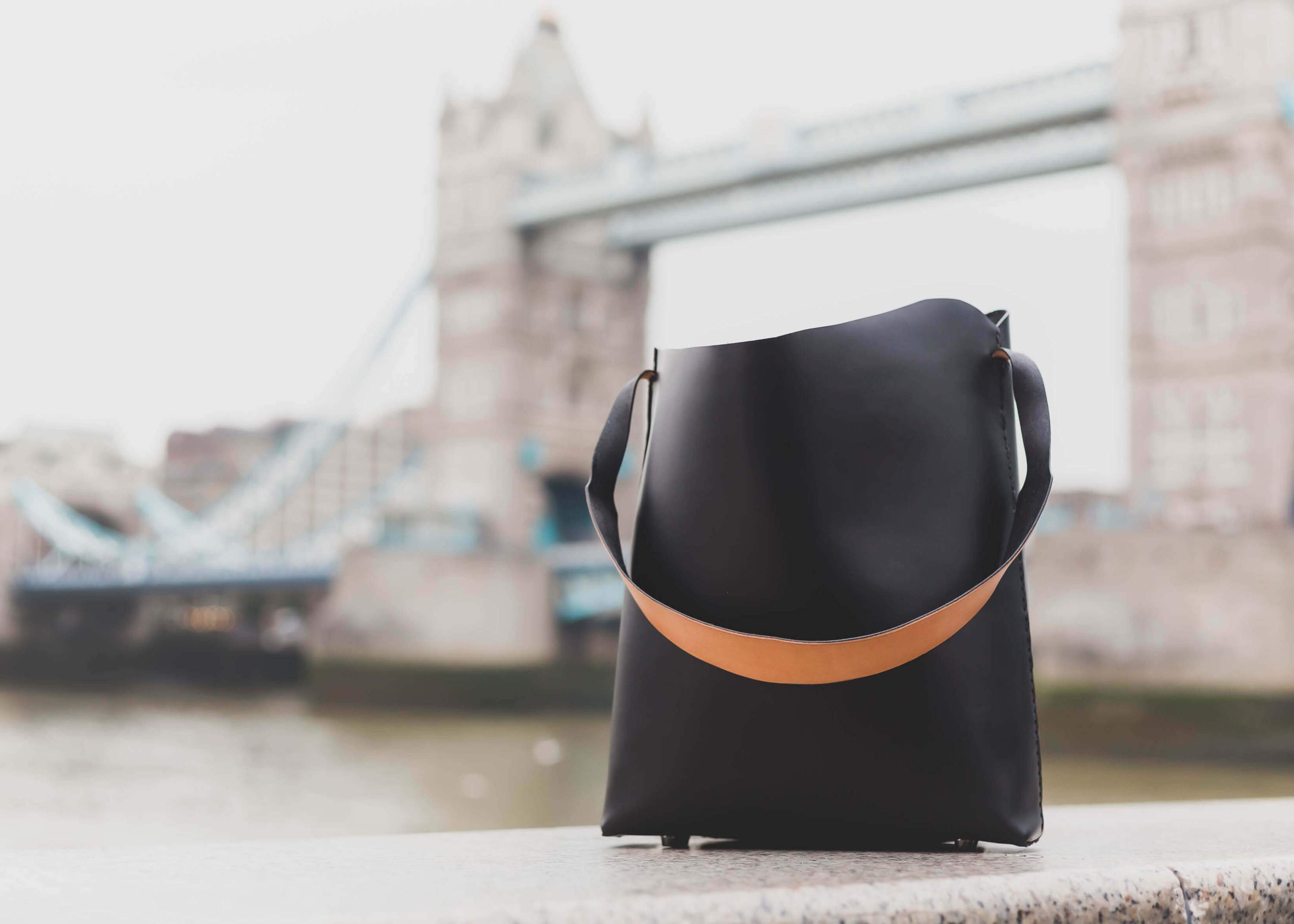 A handcrafted Bucket Tote made from vegtan leather, featuring a minimalist design and unlined interior, perfect for carrying a 13" laptop.