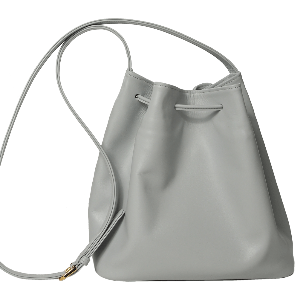 Buffed Leather Bucket Bag Pumice featuring fringed straps and gold studs, crafted from Italian calfskin with a spacious cotton interior.