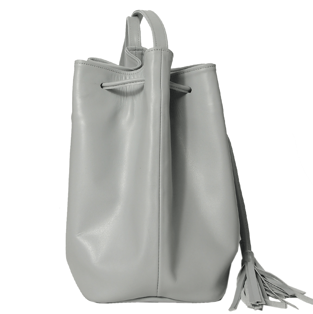 Buffed Leather Bucket Bag Pumice featuring fringed straps and gold studs, crafted from Italian calfskin with a spacious cotton interior.