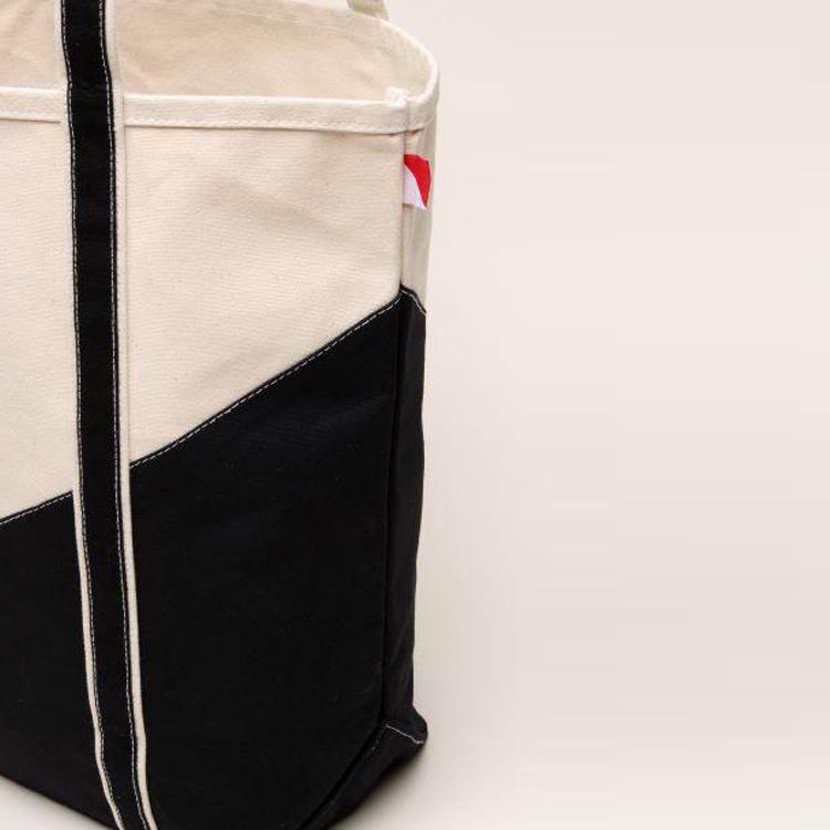 A large contemporary tote bag featuring a diagonal sail design, reinforced handles, and multiple interior pockets for organization.