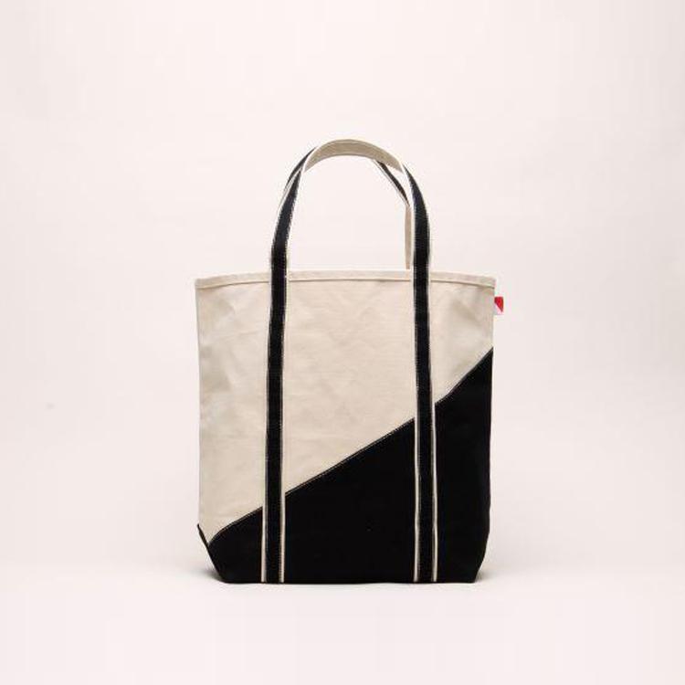 A large contemporary tote bag featuring a diagonal sail design, reinforced handles, and multiple interior pockets for organization.