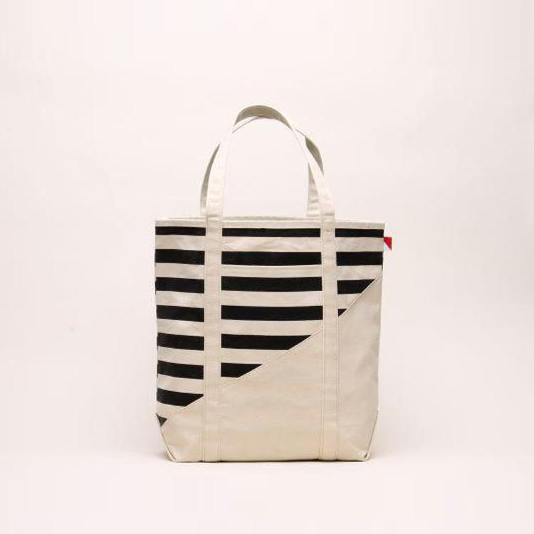 A large contemporary tote bag featuring a diagonal sail design, reinforced handles, and multiple interior pockets for organization.