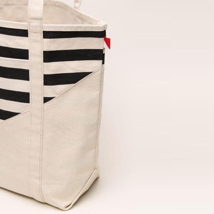 A large contemporary tote bag featuring a diagonal sail design, reinforced handles, and multiple interior pockets for organization.