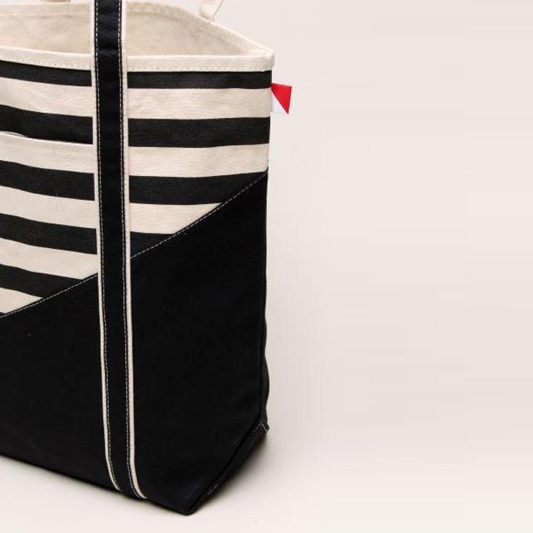 A large contemporary tote bag featuring a diagonal sail design, reinforced handles, and multiple interior pockets for organization.