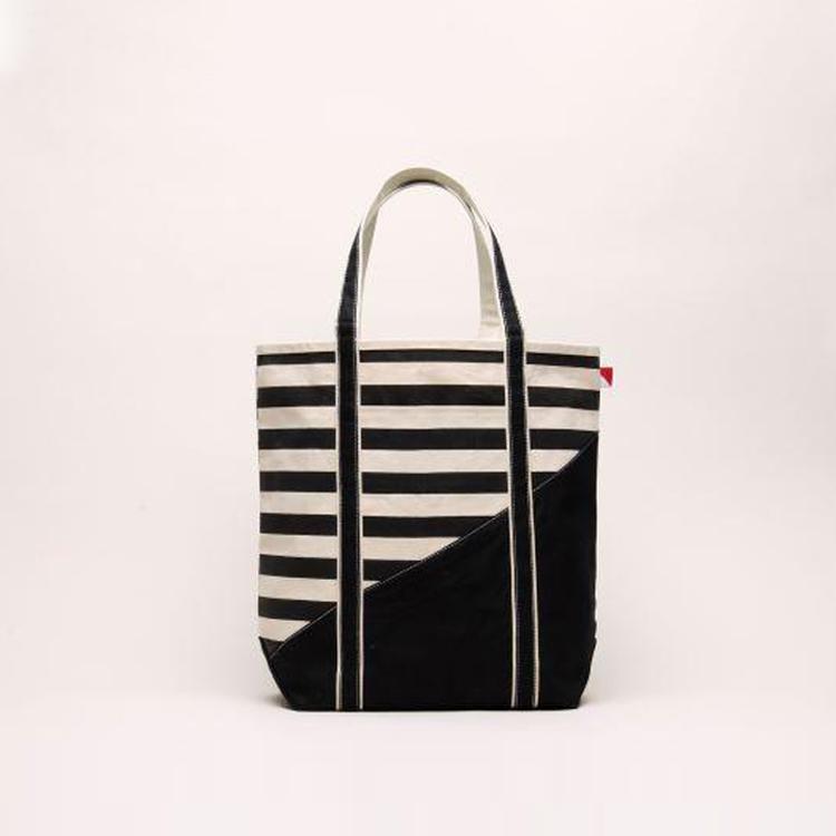 A large contemporary tote bag featuring a diagonal sail design, reinforced handles, and multiple interior pockets for organization.