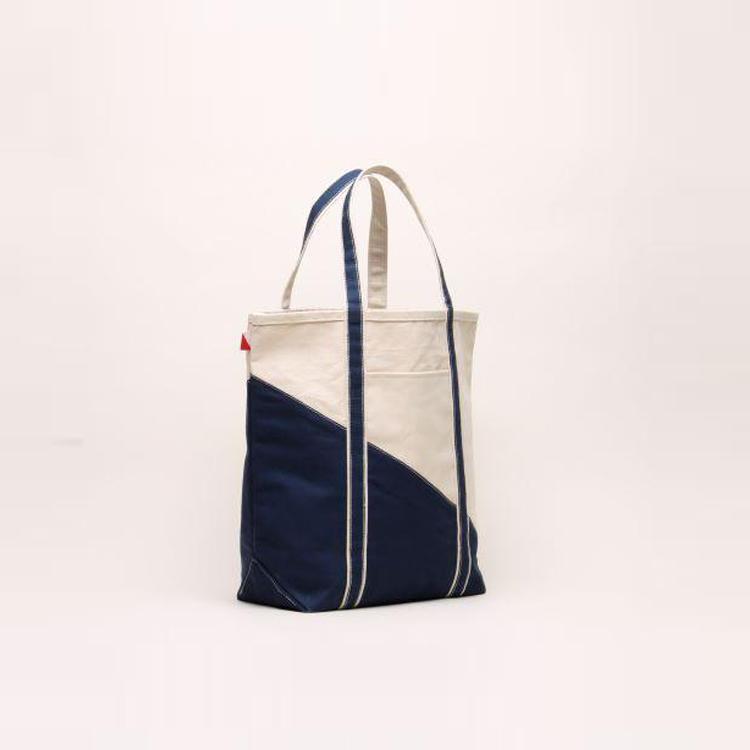 A large contemporary tote bag featuring a diagonal sail design, reinforced handles, and multiple interior pockets for organization.