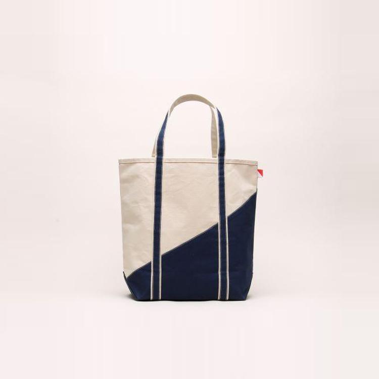 A large contemporary tote bag featuring a diagonal sail design, reinforced handles, and multiple interior pockets for organization.