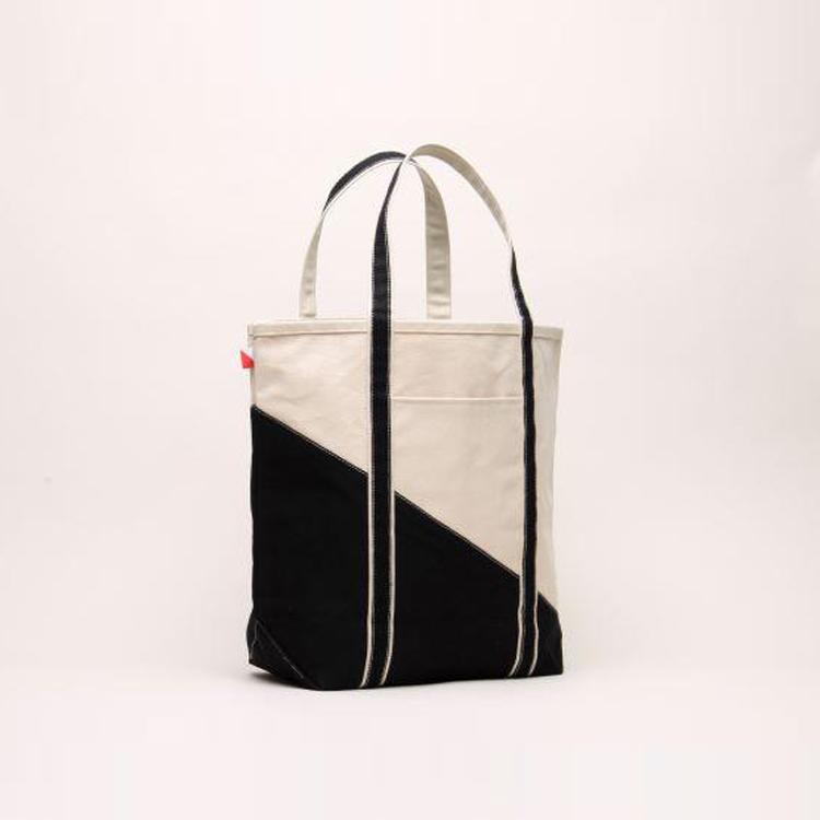 A large contemporary tote bag featuring a diagonal sail design, reinforced handles, and multiple interior pockets for organization.