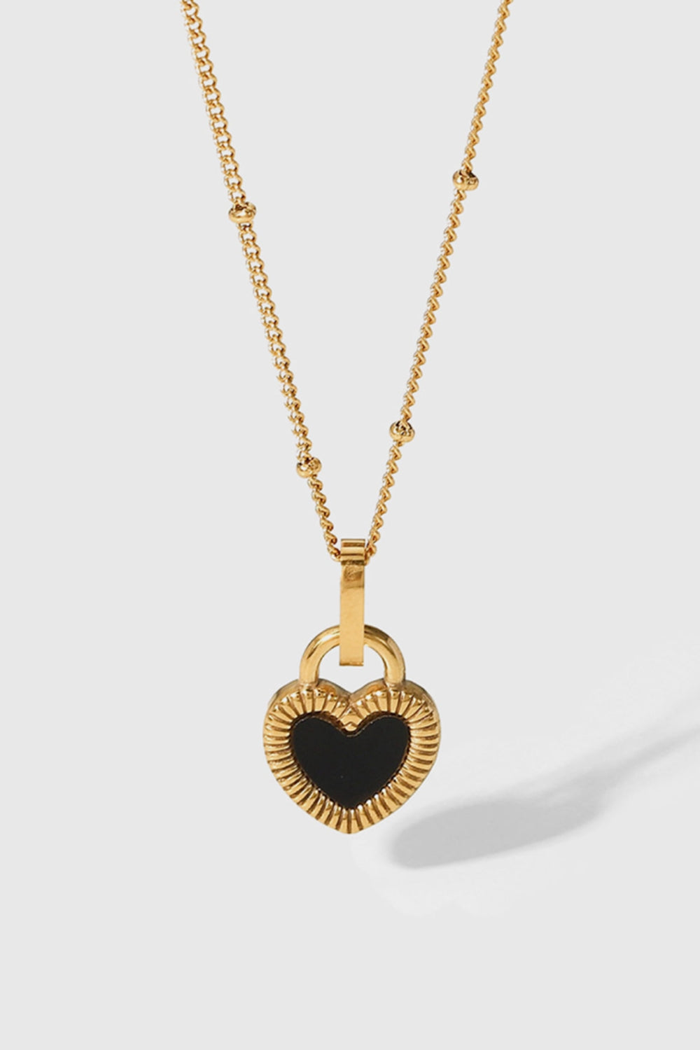 A stylish Contrast Heart Pendant Necklace featuring a heart-shaped pendant on a stainless steel chain, elegantly displayed in a flat lay style.