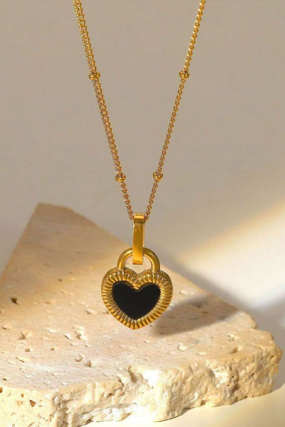 A stylish Contrast Heart Pendant Necklace featuring a heart-shaped pendant on a stainless steel chain, elegantly displayed in a flat lay style.